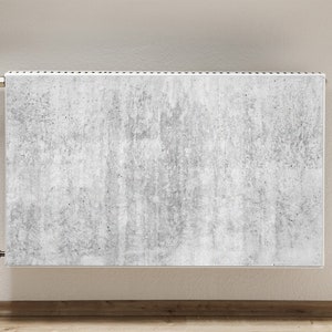 Op de afbeelding: Een witte radiator met een betonachtige afwerking. De radiator heeft twee zilveren kleppen aan de zijkanten.