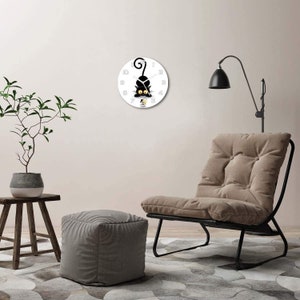 May include: A white clock with black hands and a black cat design. The cat is holding a cup of coffee and has a surprised expression. The clock is hanging on a white wall.