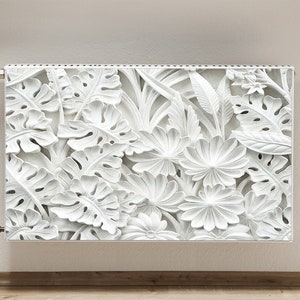 Op de afbeelding: Witte radiatorbekleding met een 3D-reliëfdesign van tropische bladeren en bloemen.