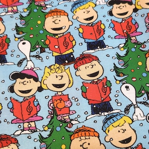 May include: Fabric featuring a repeating pattern of cartoon characters singing carols, with Christmas trees and Snoopy on a light blue background. The characters are wearing hats and holding red songbooks. The design is festive and colorful.