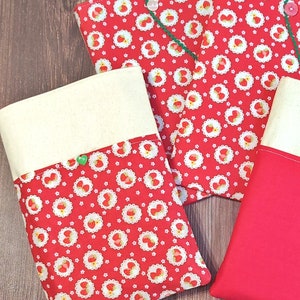 May include: Three fabric pouches with a red and white strawberry pattern. The pouches have a cream-colored flap with a green button.