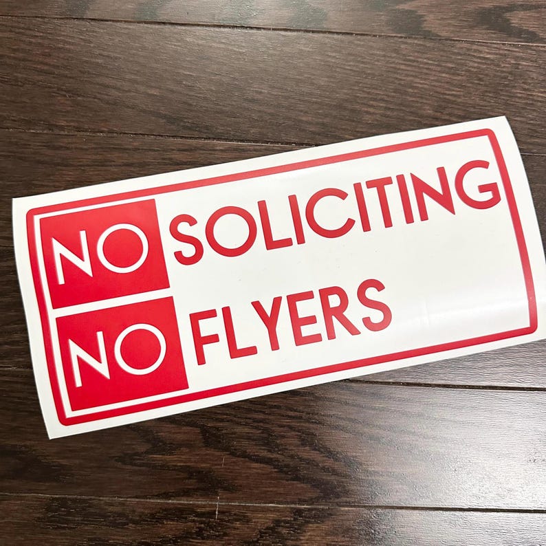 May include: White sign with red text that says "NO SOLICITING NO FLYERS".