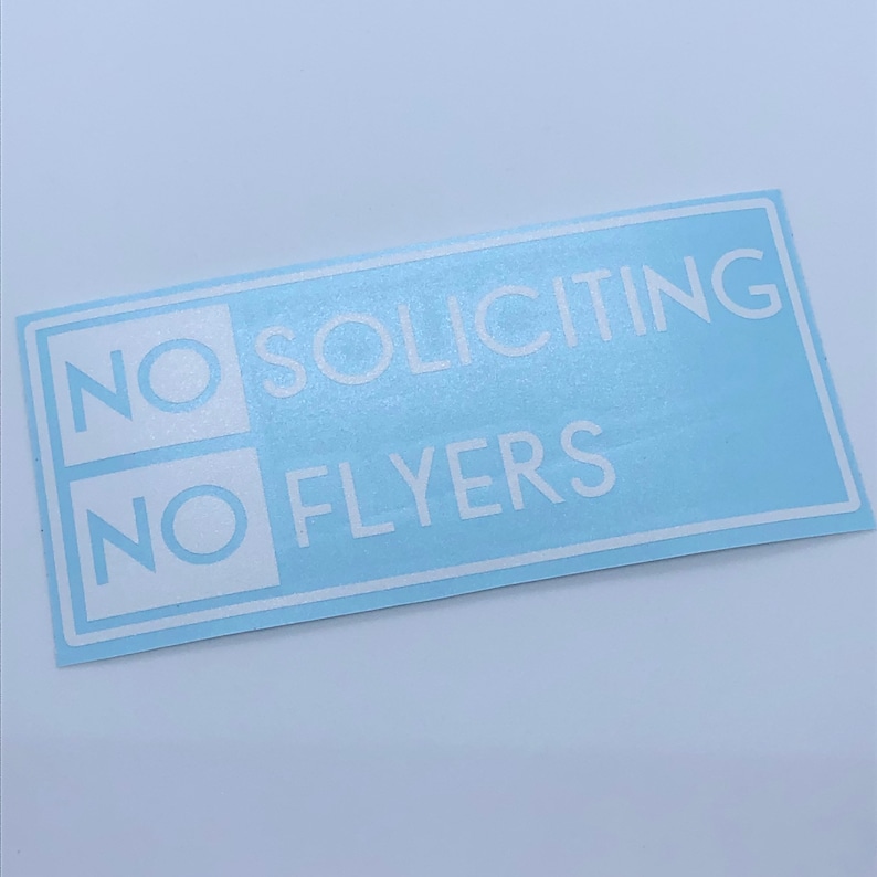 May include: A light blue sticker with white text that reads "NO SOLICITING NO FLYERS".