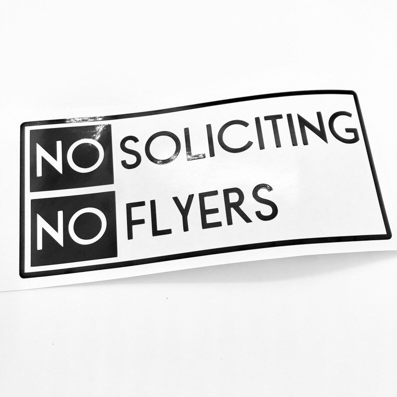 May include: Black and white sign with the text "NO SOLICITING NO FLYERS" in a bold, sans-serif font.