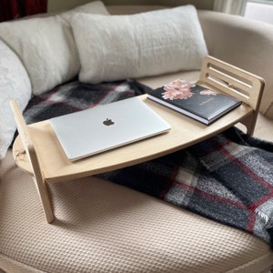 Large Adjustable lap desk shown on a couch. The desk is supporting a laptop and a note book. We can clearly see the simple assembly mechanism with slots and dowel.