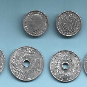 Puede incluir: Colección de monedas griegas antiguas, con varias denominaciones y diseños. Las monedas son de color plateado e incluyen retratos, coronas e inscripciones. El fondo es de color azul claro liso.