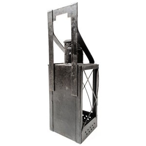 May include: A vintage black metal lantern with a handle. The lantern has a rectangular body with a glass panel and a diamond-shaped grid. The bottom of the lantern has several small holes.