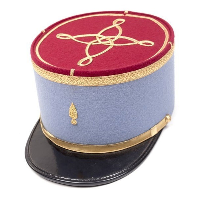May include: A vintage military hat with a red top and light blue sides. The top features gold embroidery and trim, with a gold emblem on the side. The hat has a black, glossy brim and gold accents.