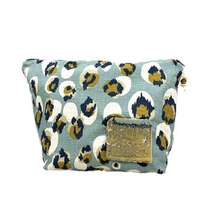 Può includere: Una pochette con cerniera di colore azzurro con un motivo a stampa leopardata. La pochette ha una piccola toppa dorata sul davanti.