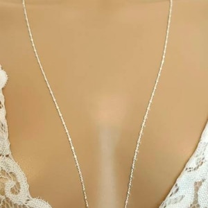 Può includere: Una delicata collana d'argento con una catena sottile. La collana è esposta su uno sfondo neutro, evidenziando la sua semplice eleganza. La catena è lunga circa 50 cm.