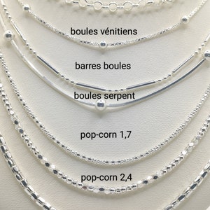 Könnte beinhalten: Nahaufnahme von sieben verschiedenen Silberketten, jede mit einem einzigartigen Muster und einem Namensschild. Die Ketten sind in einem vertikalen Stapel angeordnet, beginnend mit der größten Kette oben und endend mit der kleinsten Kette unten. Die Ketten sind wie folgt beschriftet: jaseron, boules vénitiens, barres boules, boules serpent, pop-corn 1,7, pop-corn 2,4 und corde.