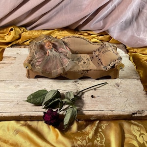 Antique small 1950s doll on fabric sofa with cushion