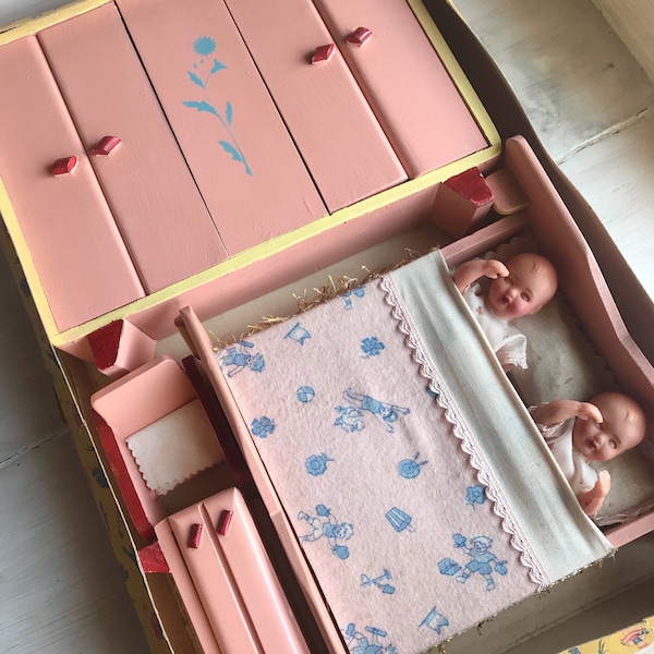 Vers 1960. Boîte de maison de poupée. Armoire, chaise, deux poupées, un lit, un miroir.