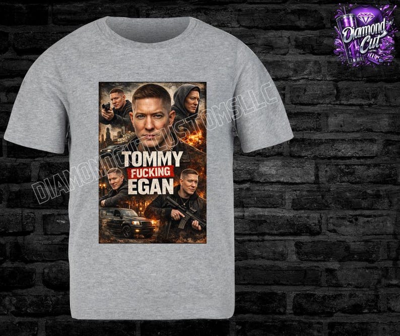 May include: A light gray t-shirt featuring a graphic of a man with the text "TOMMY FUCKING EGAN". The graphic includes images of the man in various poses. The shirt has a crew neck and short sleeves.
