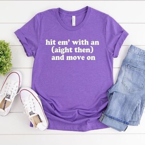 May include: Purple t-shirt with the text "hit em' with an (aight then) and move on" in white.