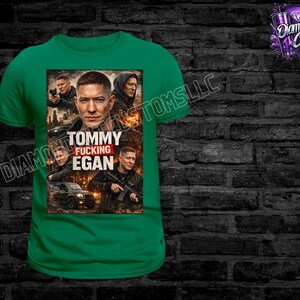 May include: A green t-shirt featuring a graphic of a man with the text "Tommy Fucking Egan". The graphic includes images of the man in various poses, with a car and city backdrop.