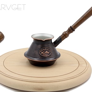 May include: A copper and wood Turkish coffee pot with a hammered finish and the word "Armenia" engraved on the side. The pot is sitting on a wooden chopping board.