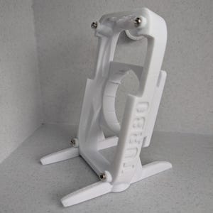 May include: A white plastic device with the word "TURBO" printed on the side. The device has a curved top with two small screws and two legs for stability. It appears to be a holder or stand.