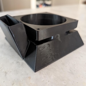 Op de afbeelding: Een zwarte 3D-geprinte kunststof adapter met een vierkante basis, een ronde opening aan de bovenzijde en een schuine, rechthoekige uitloop aan één kant. Het oppervlak vertoont zichtbare laaglijnen en de in reliëf gedrukte tekst 805 op de zijkant.