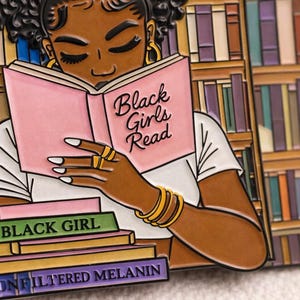 Pode incluir: Pin com uma mulher negra lendo um livro rosa com a frase "Black Girls Read". Abaixo, uma pilha de livros com os t&iacute;tulos "Black Girl" e "Unfiltered Melanin". O fundo mostra uma estante de livros.