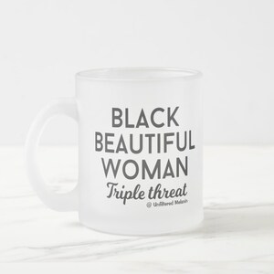 May include: Frosted white mug with a handle. The mug features the text "BLACK BEAUTIFUL WOMAN Triple threat" in dark gray, with "Triple threat" in a script font. The mug has the @Unfiltered Melanin logo.