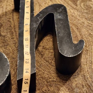 Puede incluir: Letras de metal negro, la letra "H" tiene 15 pulgadas de alto, la letra "S" tiene 10 pulgadas de alto. Las letras est&aacute;n sobre una alfombra marr&oacute;n.