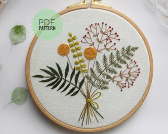 May include: Embroidered floral hoop art featuring a bouquet of yellow, green and red flowers. The hoop is made of wood and has a white fabric background.