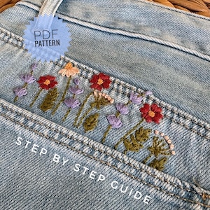 May include: Light blue denim fabric featuring a floral embroidery design with red, purple, and peach flowers and green leaves. The image includes the text PDF PATTERN and STEP BY STEP GUIDE, indicating a digital instructional resource for embroidery.