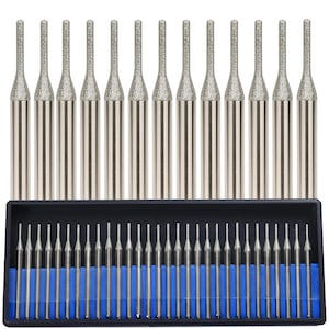 May include: A set of silver-colored rotary tool bits with diamond-coated tips. The bits are arranged in a black plastic case with blue dividers. The tips are textured and cylindrical, designed for detailed work.