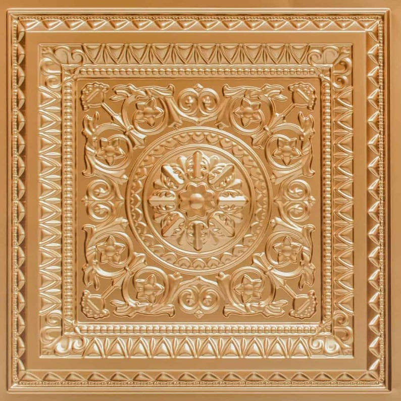 May include: A square, gold-coloured decorative ceiling tile with an ornate, embossed floral and geometric design. The central motif is a circular pattern surrounded by stylized flowers and leaves. The tile has a raised border with repeating geometric shapes.