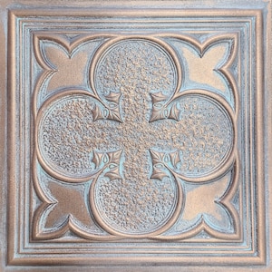 May include: A decorative tile featuring a quatrefoil design in copper and turquoise tones. The tile has a textured surface and a raised design.