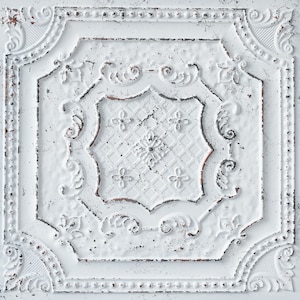 May include: White ceiling tile with a distressed, aged look. The tile features a decorative, ornate design with a central floral motif.
