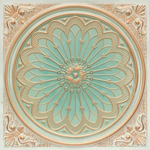 Op de afbeelding: Een decoratieve plafondtegel met een cirkelvormig ontwerp met een grote, sierlijke bloem in het midden. De bloem wordt omringd door een reeks concentrische cirkels en stralende lijnen, allemaal in een gouden metallic afwerking. De achtergrond van de tegel is lichtgroen.