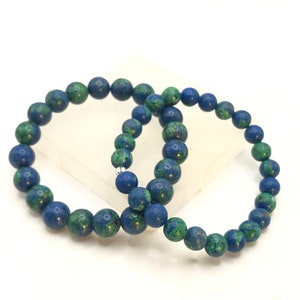 K&ouml;nnte beinhalten: Zwei blaue und gr&uuml;ne Edelstein-Armb&auml;nder mit silbernen Verschl&uuml;ssen. Die Armb&auml;nder bestehen aus runden Perlen und sind &uuml;bereinander gestapelt.