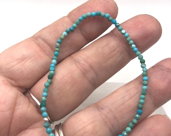 May include: A delicate turquoise beaded bracelet. The bracelet is made of small, round, turquoise beads strung together. The beads have a slightly faceted appearance, and the color is a vibrant blue-green. The bracelet is shown on a light background.