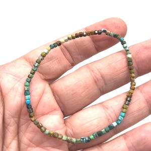 Peut inclure: Un bracelet de perles composé de petites perles carrées dans des tons turquoise, marron, vert et blanc. Le bracelet est assemblé, créant une bande souple. Les perles sont de taille et de forme uniformes, donnant au bracelet un aspect délicat.