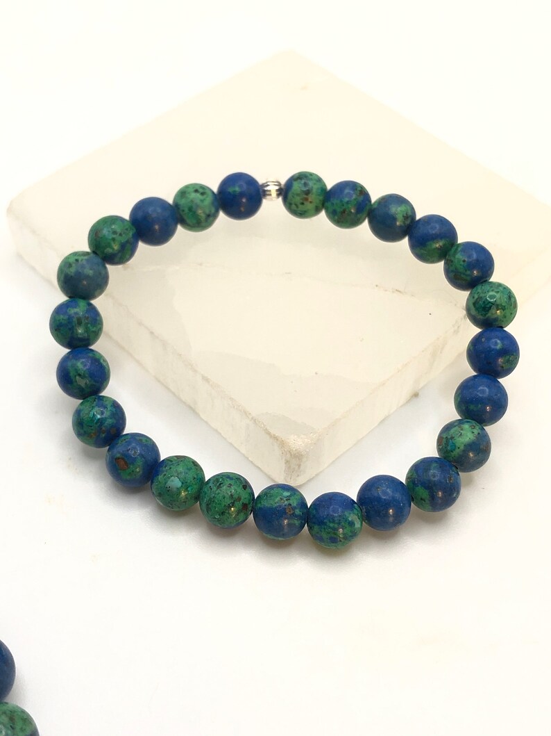 K&ouml;nnte beinhalten: Ein blaues und gr&uuml;nes Edelstein-Armband mit einem silbernen Verschluss. Das Armband besteht aus runden Perlen.