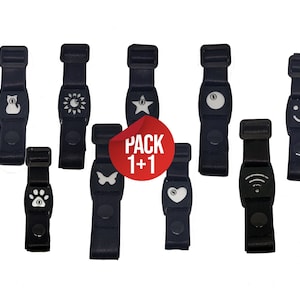 Op de afbeelding: Een verzameling zwarte verstelbare bandjes met diverse witte iconen, waaronder een kat, zon, ster, pootafdruk, vlinder, hart en smiley. De bandjes hebben een gesp en een ronde knop. Een rode sticker zegt "PACK 1+1".