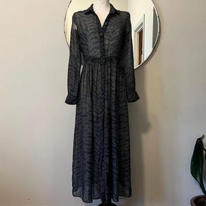 May include: A long-sleeved black and gray patterned dress with a button-up front and a gathered waist.