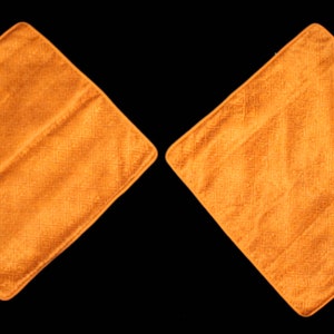 Puede incluir: Dos cojines de sofá de color naranja en forma de diamante con una superficie de tela texturizada.