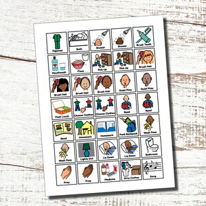 May include: A printed sheet with a grid of illustrated icons representing daily routines. Icons include pajamas, brushing teeth, showering, and packing a backpack. The sheet is on a white background with a wooden texture.