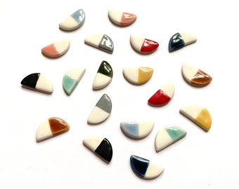 May include: Assortment of ceramic half-circle tiles with various color combinations. The tiles are white on one side and feature a variety of colors on the other side, including red, blue, green, yellow, and black.