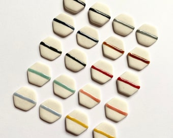 May include: Twenty-one ceramic hexagonal tiles with a white background and a single colored stripe across the center. The stripes are in various colors, including black, blue, green, red, orange, brown, and yellow.