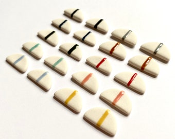 May include: A collection of 18 ceramic half-circle tiles with a white base and a single colored stripe across the center. The stripes are in various colors, including red, blue, yellow, green, and brown.