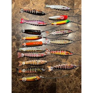 May include: A collection of 10 colorful segmented fishing lures with silver chains. The lures are painted with realistic fish patterns and have a variety of colors, including red, orange, yellow, green, blue, and black.