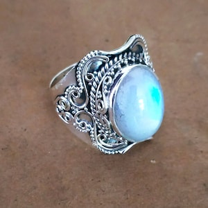 Può includere: Un anello d'argento con una pietra di luna ovale incastonata in un design a filigrana.