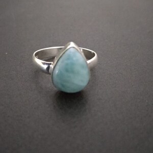 Puede incluir: Un anillo de plata con una piedra preciosa de aguamarina azul en forma de lágrima.
