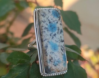 May include: A silver ring with a rectangular blue and white stone set in a beaded bezel.