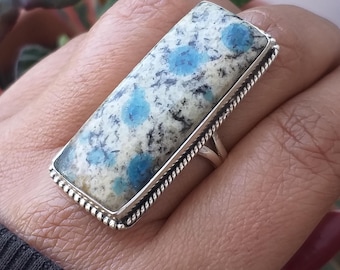 May include: A silver ring with a rectangular blue and white kyanite gemstone. The ring has a rope-like design around the edge of the setting.