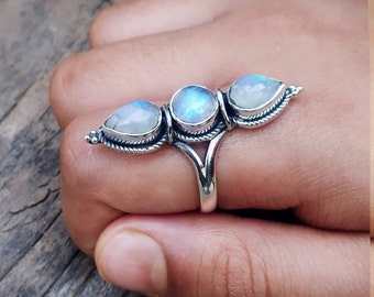 May include: A silver ring with three teardrop-shaped moonstone gems set in a delicate silver band.